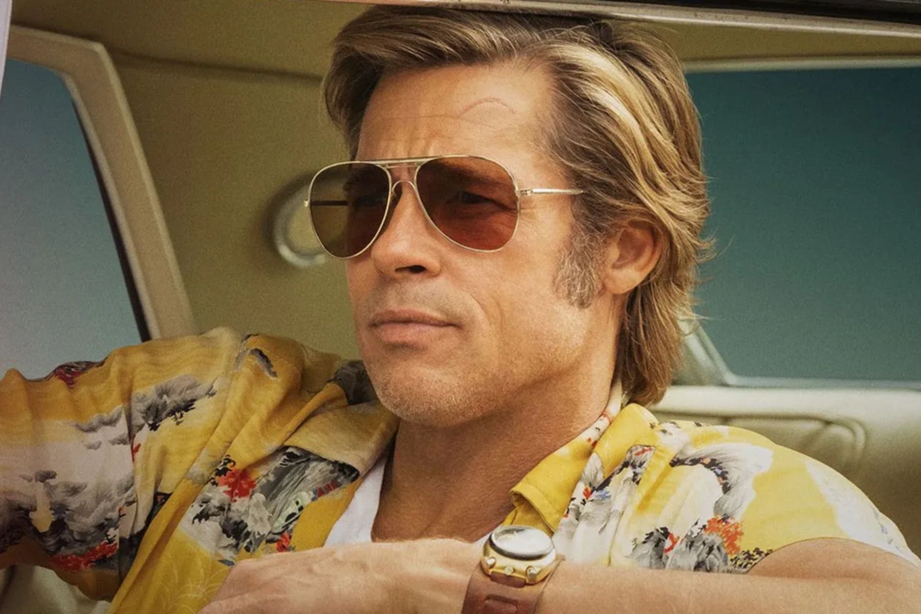 Brad Pitt caracterizado como Cliff Booth con lentes de sol y camisa hawaiana en el set de filmación.