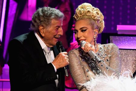 Lady Gaga vestida de gala cantando en el escenario junto a Tony Bennett frente a micrófonos clásicos.