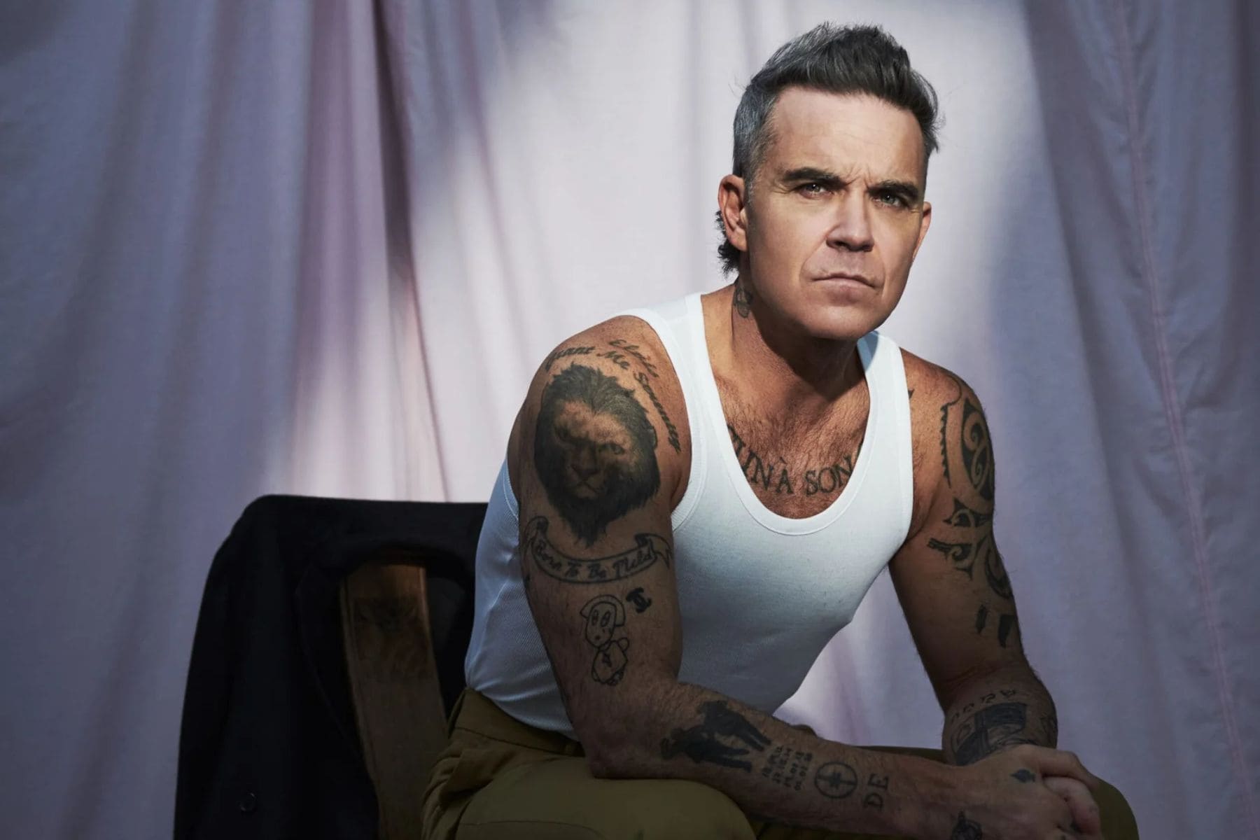 Robbie Williams cantando el corte comercial Angels en vivo durante un concierto internacional.