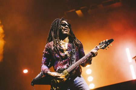 Lenny Kravitz tocando una guitarra eléctrica Gibson Flying V en el escenario.