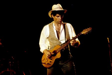 Lindsey Buckingham tocando la guitarra eléctrica sin púa durante un concierto de Fleetwood Mac.