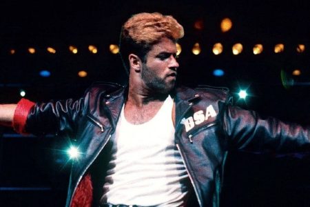 George Michael cantando con chaqueta de cuero y lentes oscuros en los premios MTV de 1989.