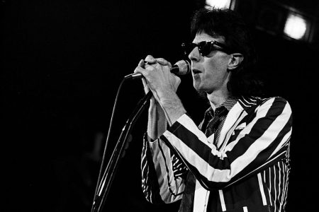 Ric Ocasek trabajando en un estudio de grabación con una consola de audio, representando su labor como productor musical de rock.