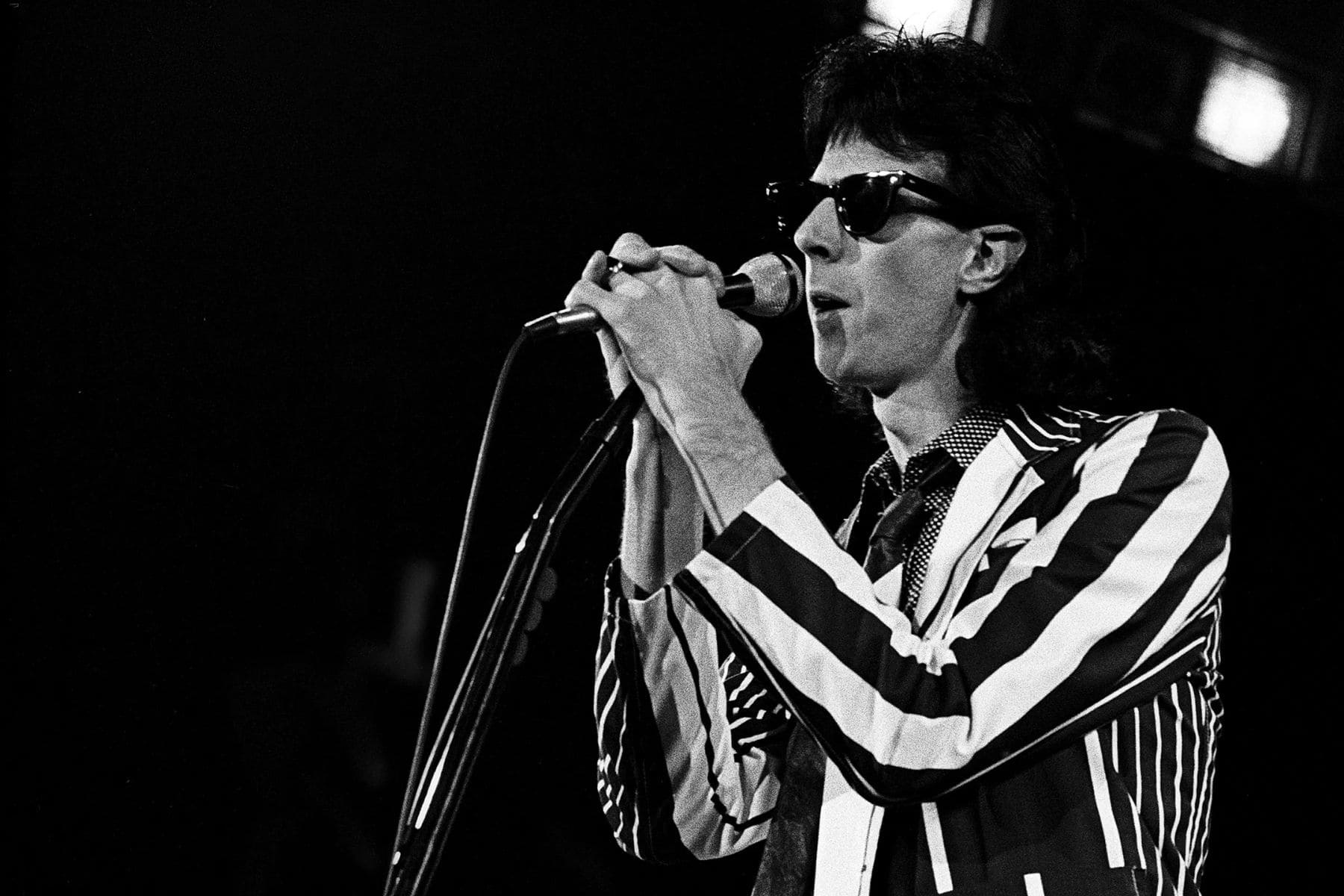 Ric Ocasek trabajando en un estudio de grabación con una consola de audio, representando su labor como productor musical de rock.