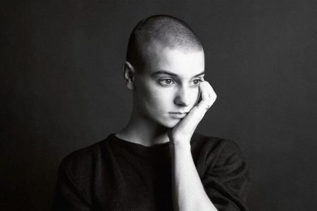Retrato artístico de Sinéad O’Connor cantando con intensidad ante el micrófono.