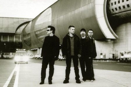 Bono cantando con los brazos abiertos en un concierto de U2.
