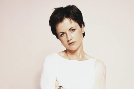 Dolores O'Riordan interpretando un tema con los brazos abiertos en un concierto.