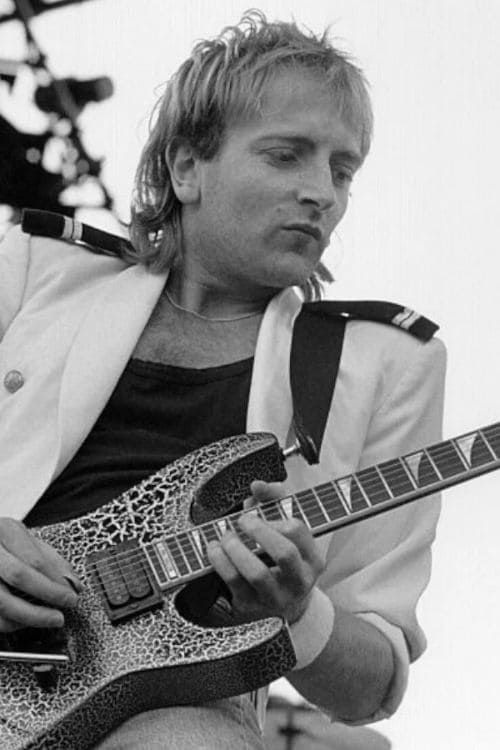 Phil Collen tocando la guitarra eléctrica en un concierto de Def Leppard.
